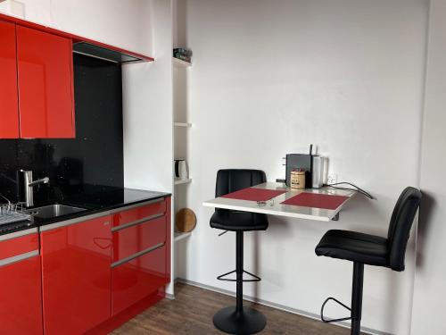a kitchen with red cabinets and two black stools at Haus Rosa in Zermatt