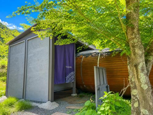 a wooden building with a garage next to a tree at tocoro. Mt. Fuji Mutsuki in Fujikawaguchiko
