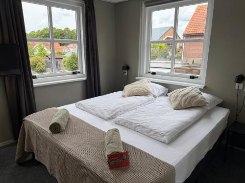 a bed in a bedroom with two windows at Hotel Willemstad - kleinschalig hotel in Willemstad