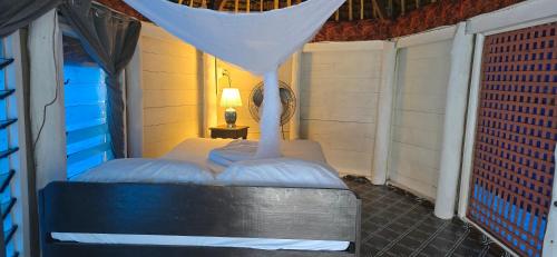 a bed in a room with a mosquito net at Lauiula Beach Club in Pu‘apu‘a