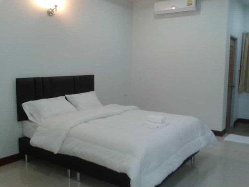 a bed with white sheets and pillows in a room at N-Joy Place in Surin