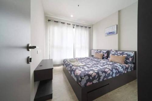 a bedroom with a bed and a desk and a window at The Base Pattaya Seaview Condo in Pattaya