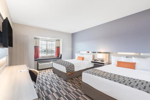 a hotel room with two beds and a television at Microtel Inn & Suites by Wyndham Perry in Perry