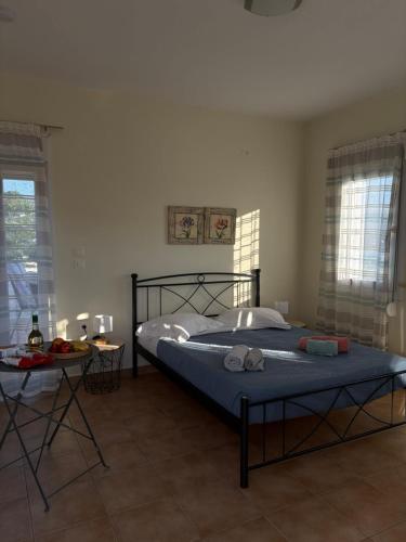 a bedroom with a bed and a table and windows at Leros 'Sundown' Guest house in Gourna