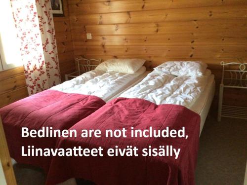two beds in a wooden room with avertisement for at Koli country club basic 6 in Hattusaari