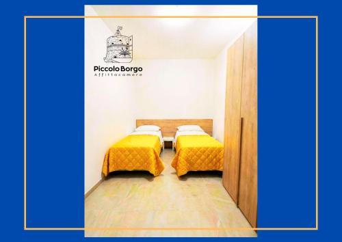 two beds in a small room with yellow covers at Piccolo Borgo Affittacamere BIKE FRIENDLY in Taranto