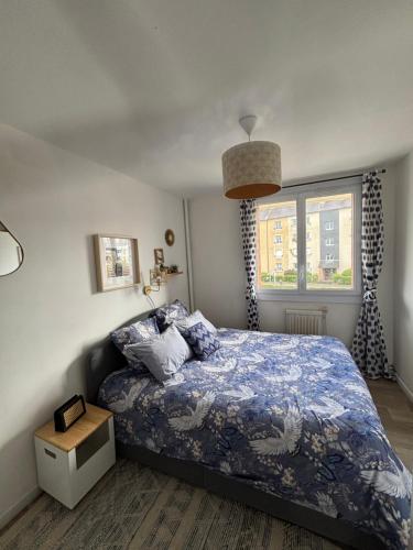 a bedroom with a bed with a blue comforter and a window at Bel appartement spacieux ,convivial de 3 chambres avec parking privé sécure in Caen