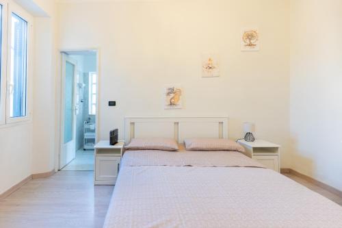 a white bedroom with two beds and two tables at Zen Retreat per Coppie con Jacuzzi - Dehor e Garage Privato - Check in Automatico e Climatizzatore in Casale Monferrato