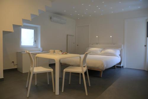 1 dormitorio con 1 cama, mesa y sillas en Duo Rooms en Mondovì