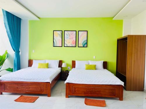 two beds in a room with green walls at VyVy House Hotel in Tuy Hoa