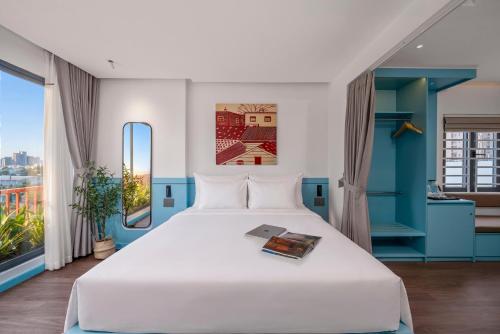 a bedroom with a large white bed and a window at The Locals Hotel - Dinh Thi Hoa Da Nang in Danang