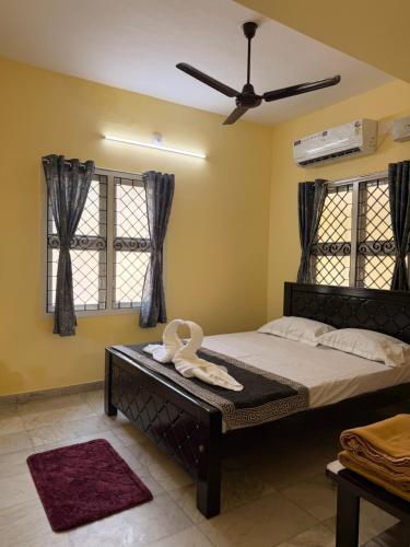 a bedroom with a bed with a fan and windows at Villa Yogalakshmi in Chidambaram