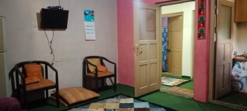 a room with two chairs and a mirror and a television at Mullberry Lodge Gulmit in Chamangul
