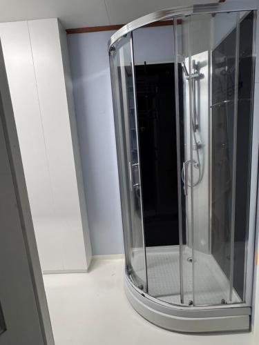 a glass shower in a room with a white cabinet at Rent Apartament Lofoten in Svolvær