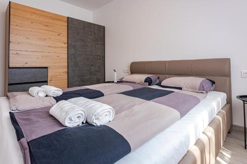 three beds in a room with towels on them at Grey Suites Pécs in Pécs