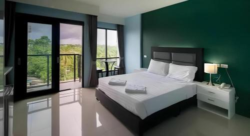 a bedroom with a large bed with a green wall at Sixty-Sixplace in Ban Khok Lo