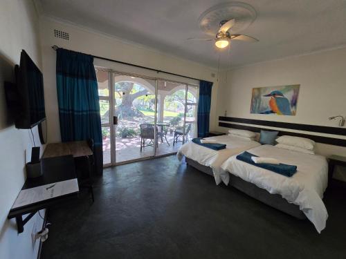 a bedroom with two beds and a television and a balcony at Hills and Dales Accommodation in Lanseria