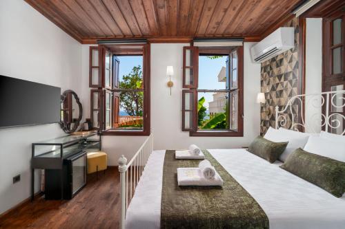a bedroom with a bed and a desk and windows at Kalkan Port Hotel in Kaş