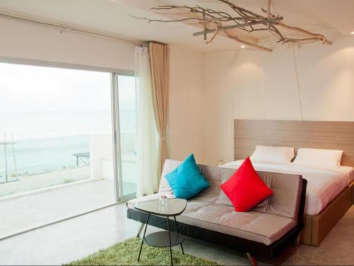 a bedroom with a bed and a couch with colorful pillows at Red Z The Ocean in Ban Tanot Noi