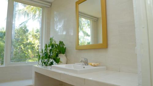a white bathroom with a sink and a mirror at Amandalay Hotel & Villas in Karimunjawa