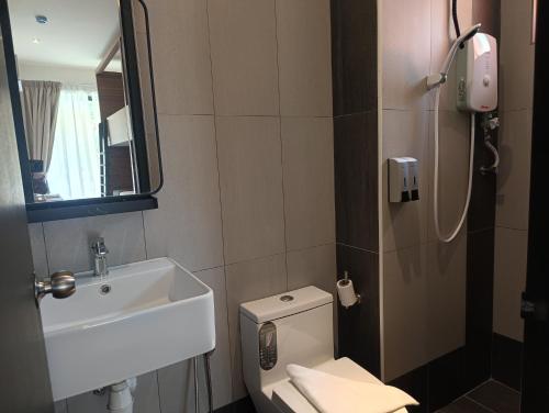 a bathroom with a toilet and a sink and a mirror at ClubRock Perlis Signature Hotel in Kaki Bukit