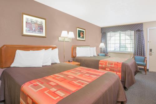 a hotel room with two beds and a chair at Travelodge by Wyndham Mansfield in Mansfield