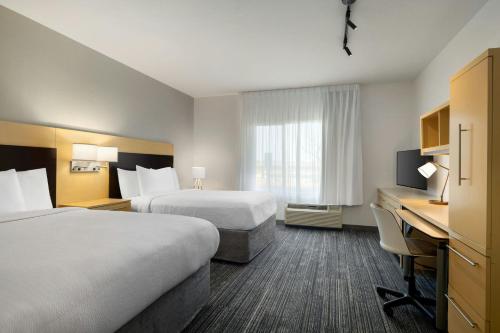 a hotel room with two beds and a desk at TownePlace Suites by Marriott Phoenix Goodyear in Goodyear
