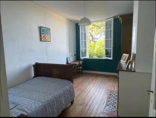 a bedroom with a bed and a table and a window at Le logis d Adrien in Saint-Magne-de-Castillon