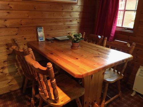 a wooden table and chairs in a wooden cabin at Lurchers Cabin Aviemore in Aviemore
