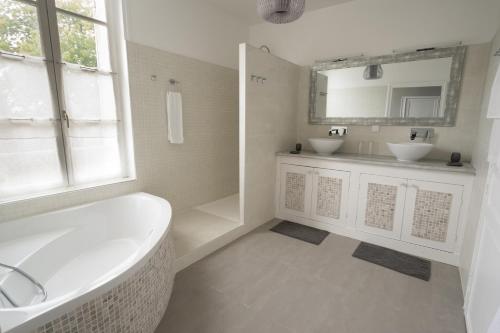 a white bathroom with two sinks and a tub at La Tillaie SPA et Sauna in Pont-lʼAbbé-dʼArnoult