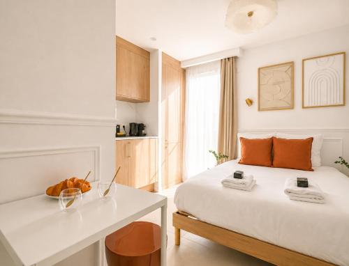 a bedroom with a white bed and a white desk at JIJI Suites Sénart in Combs-la-Ville