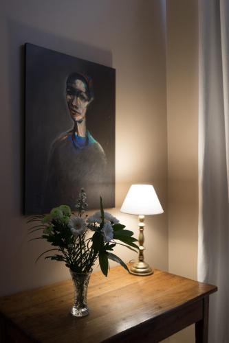 a vase of flowers on a table with a painting at La Tillaie SPA et Sauna in Pont-lʼAbbé-dʼArnoult
