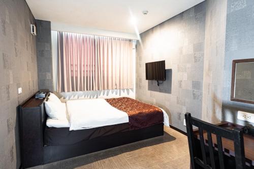 a bedroom with a bed and a television in it at ホテル ニューウェーブ in Okayama