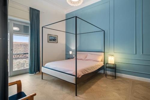a bedroom with a canopy bed in a blue room at Borgogna Living in Vercelli
