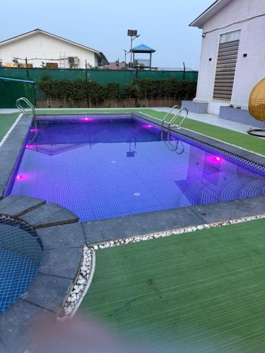 a swimming pool with purple lights in a house at Oliv Faram house in Greater Noida