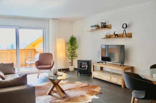 a living room with a couch and a tv at Apartment Arvenwald in Kandersteg