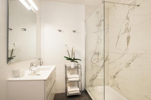 a white bathroom with a shower and a sink at Leonardo Med Spa Resort in Nondorf