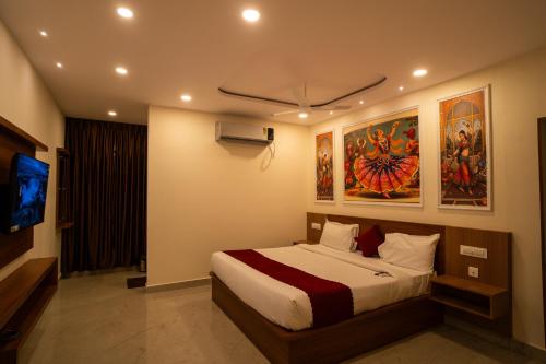 a bedroom with a bed and a tv and paintings at Magnet Hotel in Vijayawāda