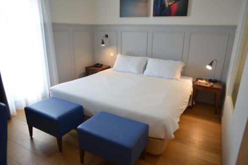 a bedroom with a large white bed with two blue stools at Charming Blue in Vila do Porto