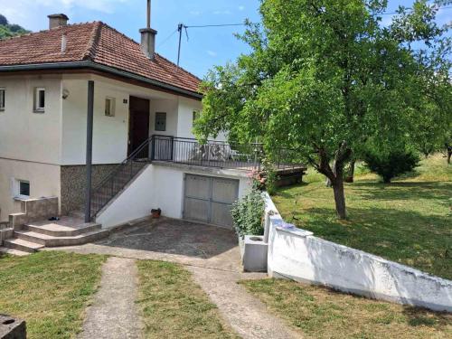 a white house with a porch and a tree at Apartman Dream in Foča