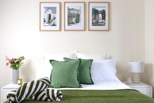 a bedroom with a bed with green and white pillows at The Olive Edit in Batemans Bay
