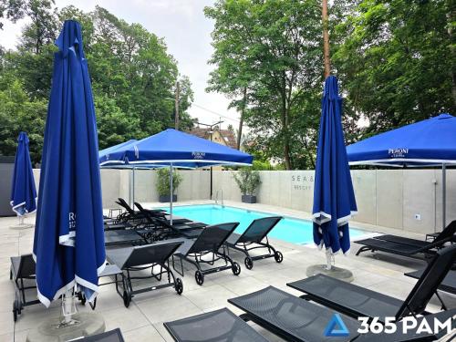 a swimming pool with blue umbrellas and chairs and a swimming pool at 365PAM - Apartament Sea & Forest - BASEN KRYTY I ZEWNĘTRZNY, JACUZZI, SAUNA, GARAŻ W CENIE in Międzyzdroje