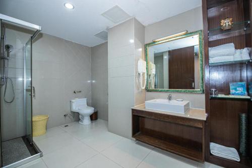 a bathroom with a sink and a toilet and a mirror at Shunde Emperor Hotel in Shunde