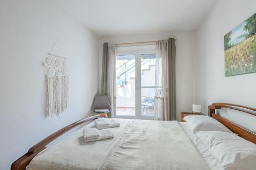 a white bedroom with a bed and a window at Iraklitsa View in Iraklitsa
