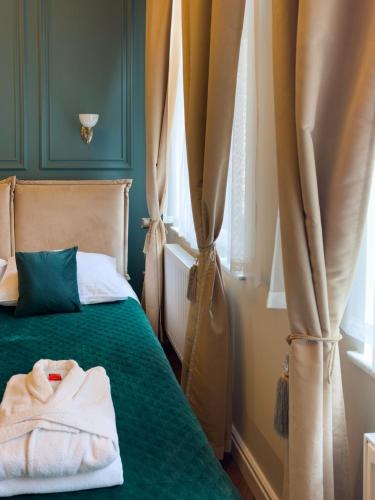 a bedroom with a bed with a green blanket and curtains at Apartament z Jacuzzi Kraków ART Koletek in Krakow