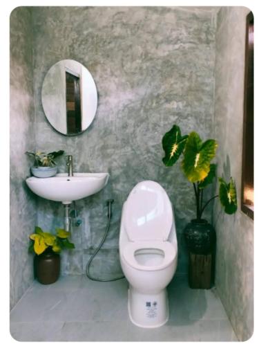 a bathroom with a white toilet and a sink at Tamarind nest in Sai Yok