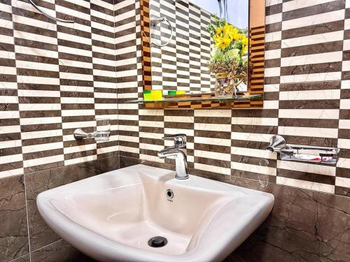 a white sink in a bathroom with a checkered wall at Seven Minutes Ella by SANS in Ella