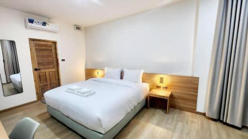 a bedroom with a white bed and a desk with a chair at Mark Four Place Hotel in Phrae
