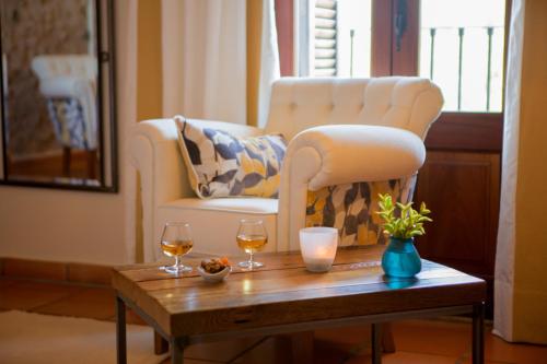 a living room with a chair and a table with wine glasses at Casa Font i Roig in Maria de la Salut
