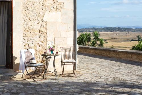 a patio with two chairs and a table with flowers at Casa Font i Roig in Maria de la Salut